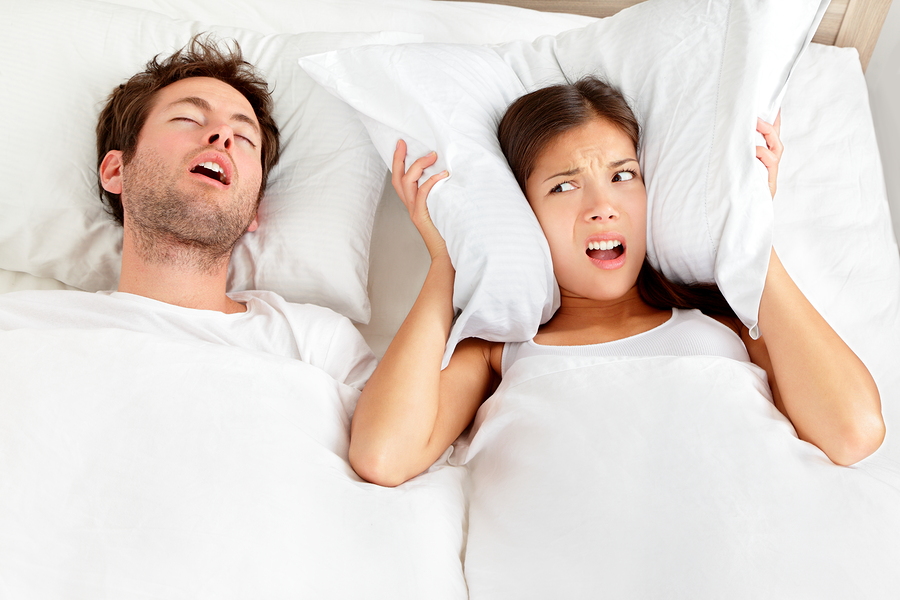 man snoring in bed, next to woman covering ears with pillow, Crittenden, KY sleep apnea oral appliance therapy